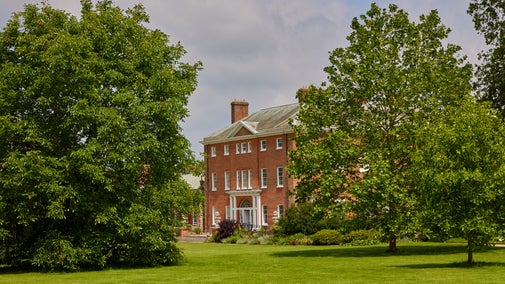 Exterior view of Hatchlands house with a lawn and trees in front of the house